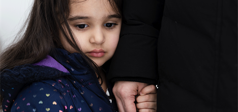sad child holding hand of parent at funeral